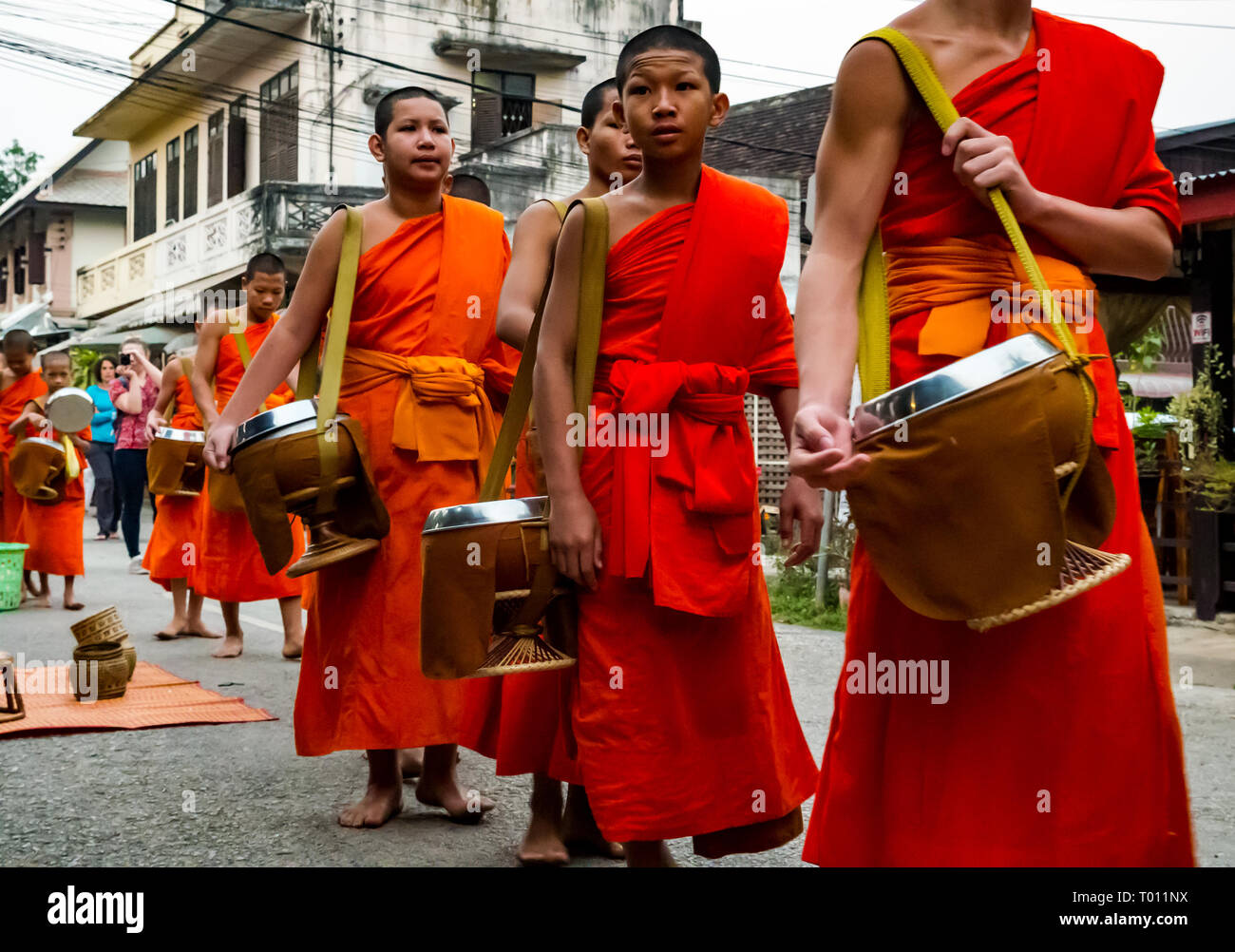 I monaci buddisti in arancione vesti coda per mattina alms dando cerimonia, Luang Prabang, Laos Foto Stock