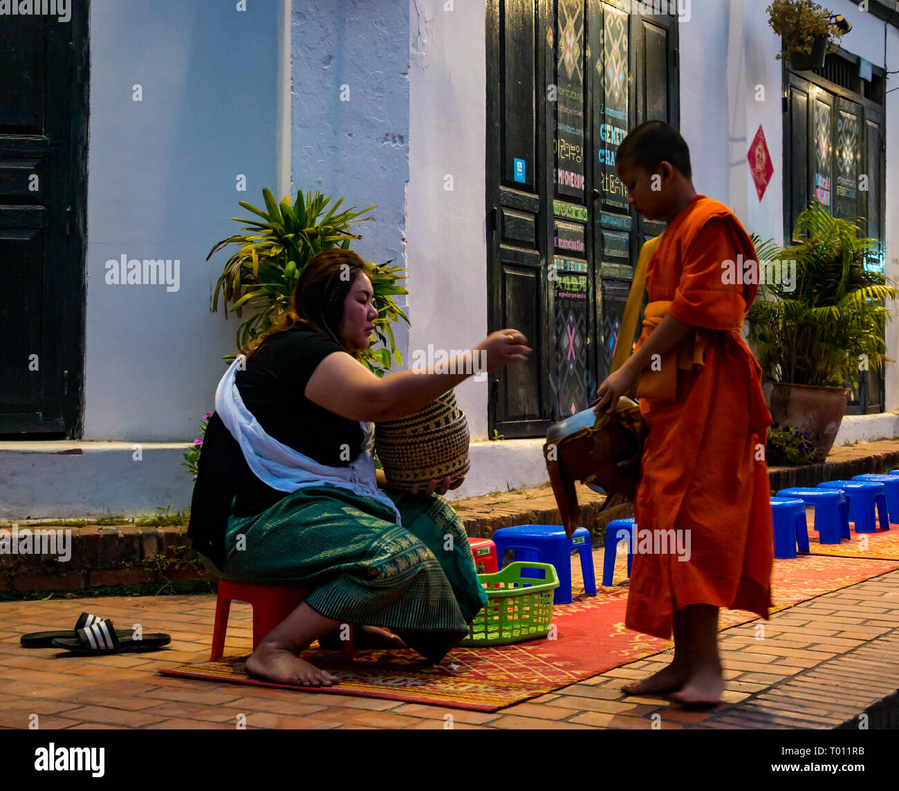 Donna consegnando il riso in ALMS mattina cerimonia di consegna per i monaci buddisti, Luang Prabang, Laos Foto Stock