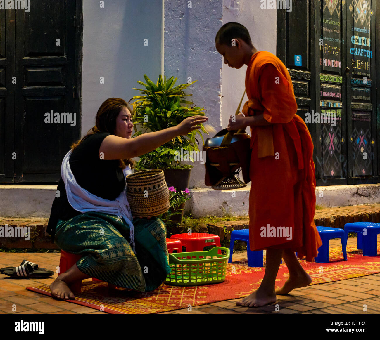 Donna consegnando il riso in ALMS mattina cerimonia di consegna per i monaci buddisti, Luang Prabang, Laos Foto Stock