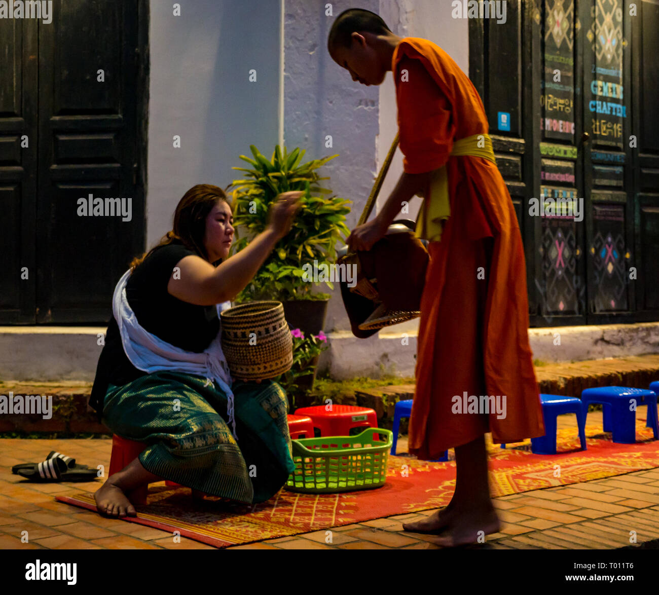 Donna consegnando il riso in ALMS mattina cerimonia di consegna per i monaci buddisti, Luang Prabang, Laos Foto Stock