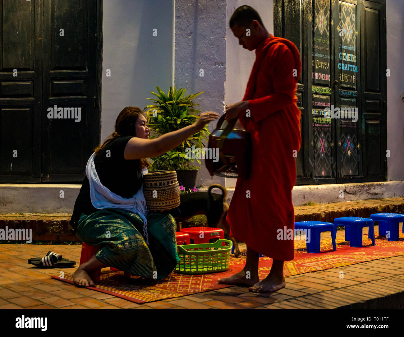 Donna consegnando il riso in ALMS mattina cerimonia di consegna per i monaci buddisti, Luang Prabang, Laos Foto Stock