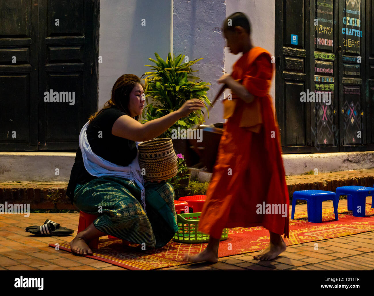 Donna consegnando il riso in ALMS mattina cerimonia di consegna per i monaci buddisti, Luang Prabang, Laos Foto Stock