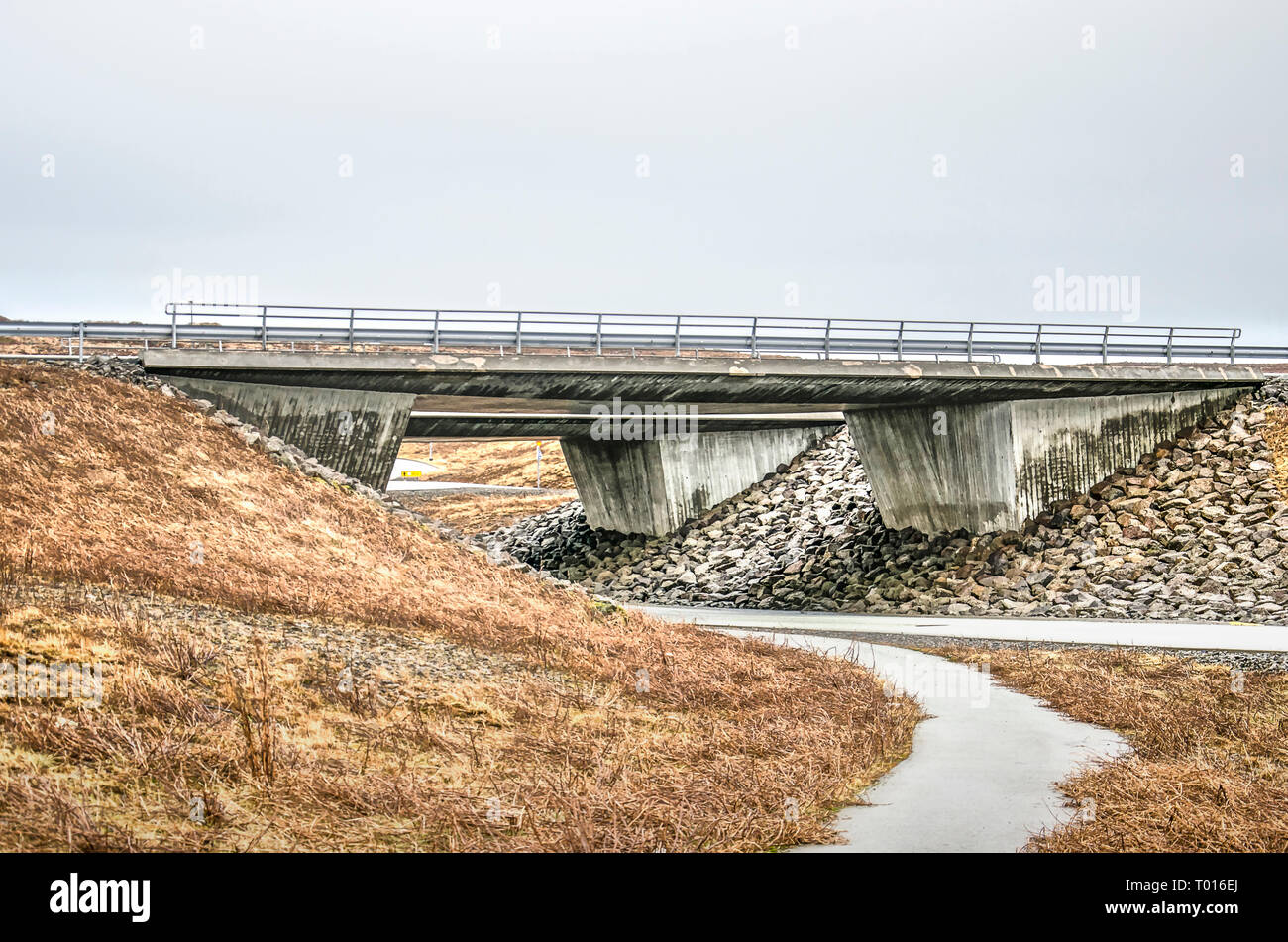 Robusto il viadotto di cemento in un'autostrada vicino a Reykjavik, Islanda, con una strada secondaria passando al di sotto di Foto Stock