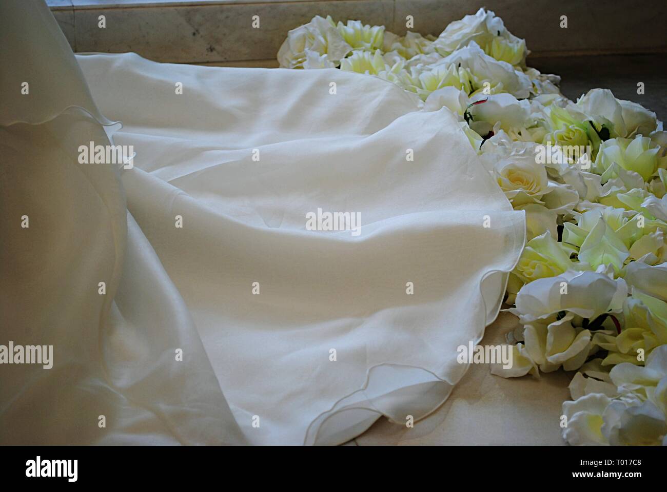 Coulisse di un bianco abito da sposa con il bianco e il giallo di rose sul pavimento Foto Stock