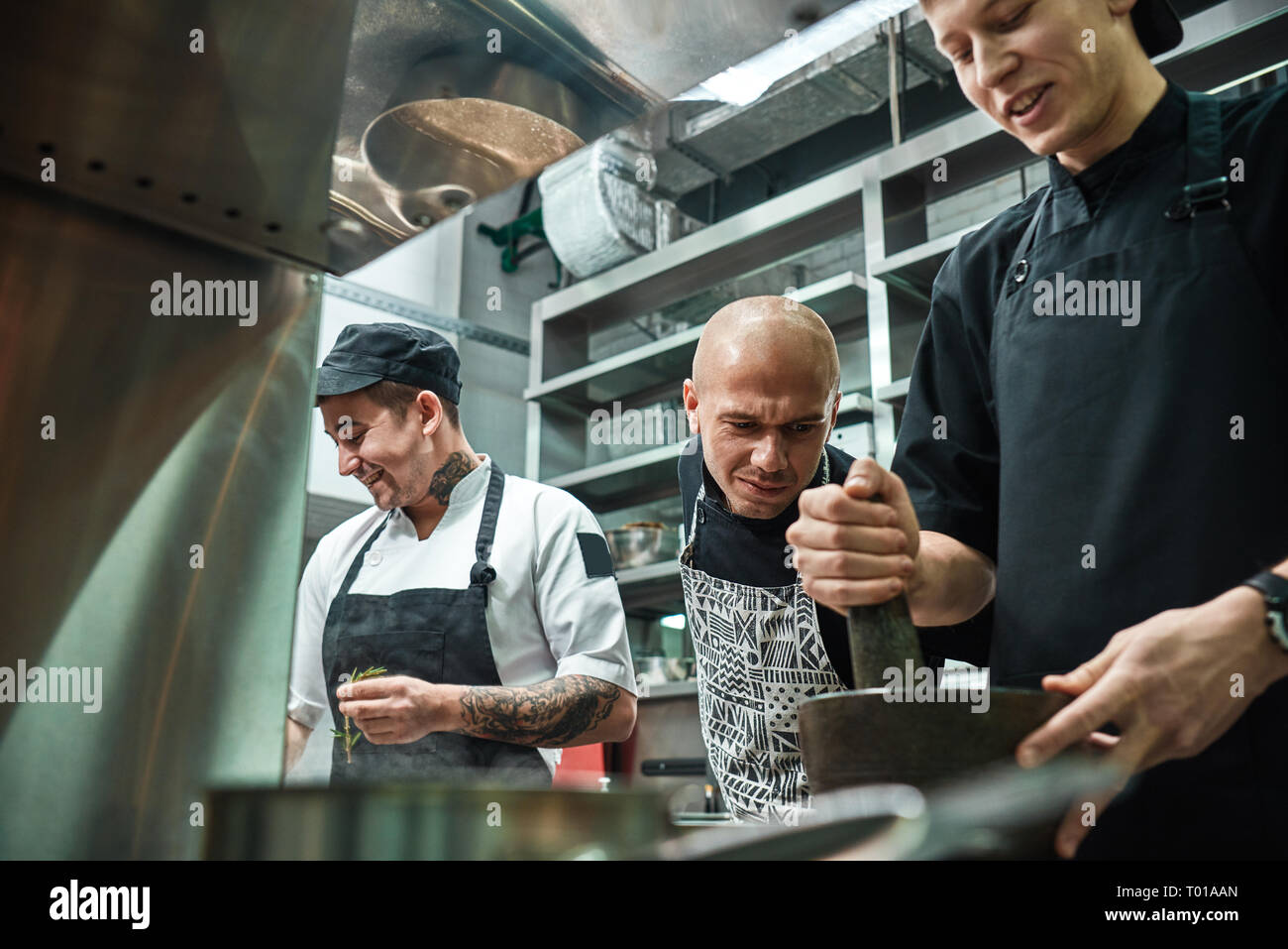 Sto guardando la rigorosa chef in grembiule guardando attentamente come il suo lavoro di assistente presso il ristorante la cucina. Concetto di cucina a vista. Foto Stock