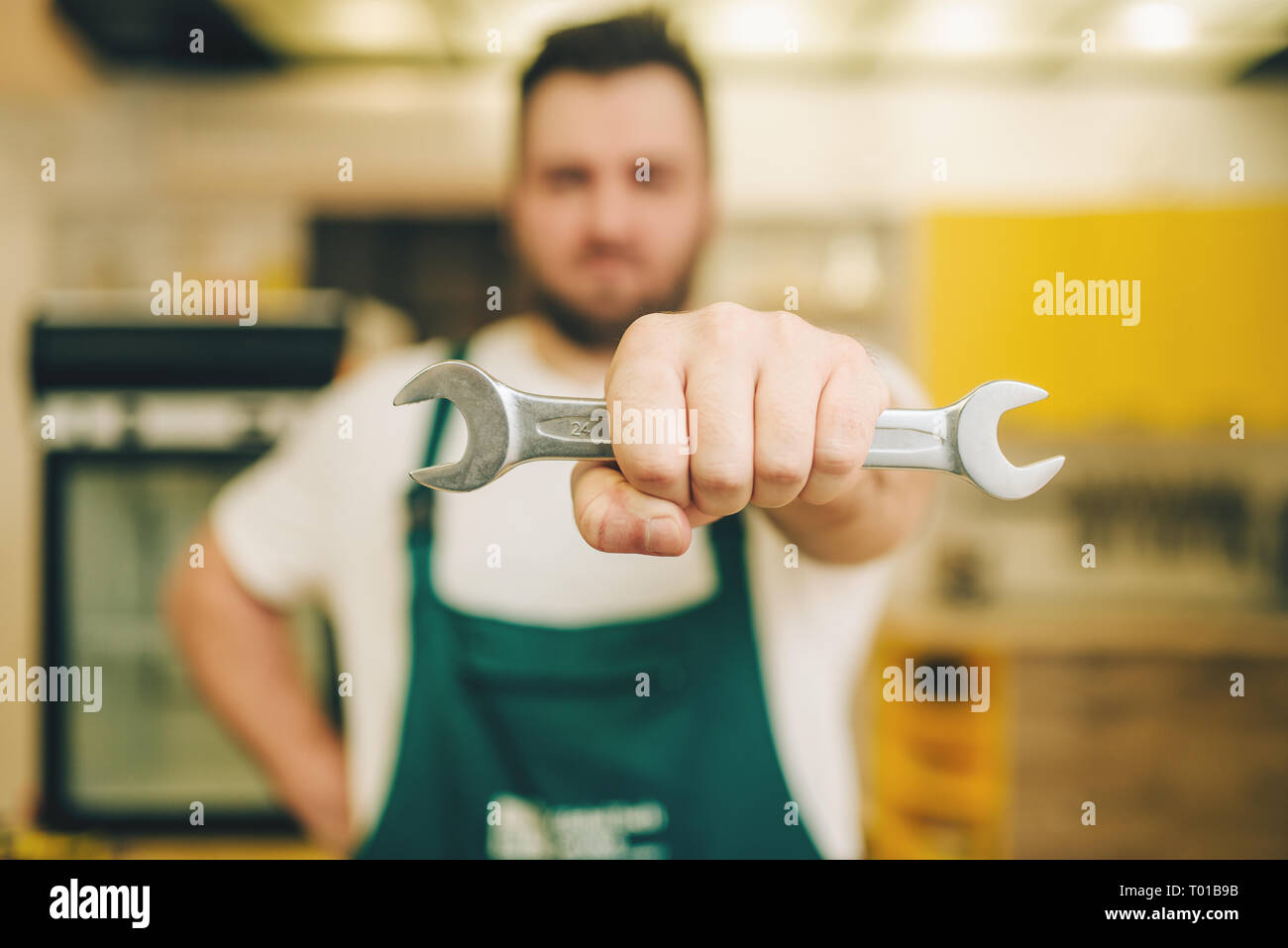 Repairman in uniforme mantiene la chiave tuttofare Foto Stock