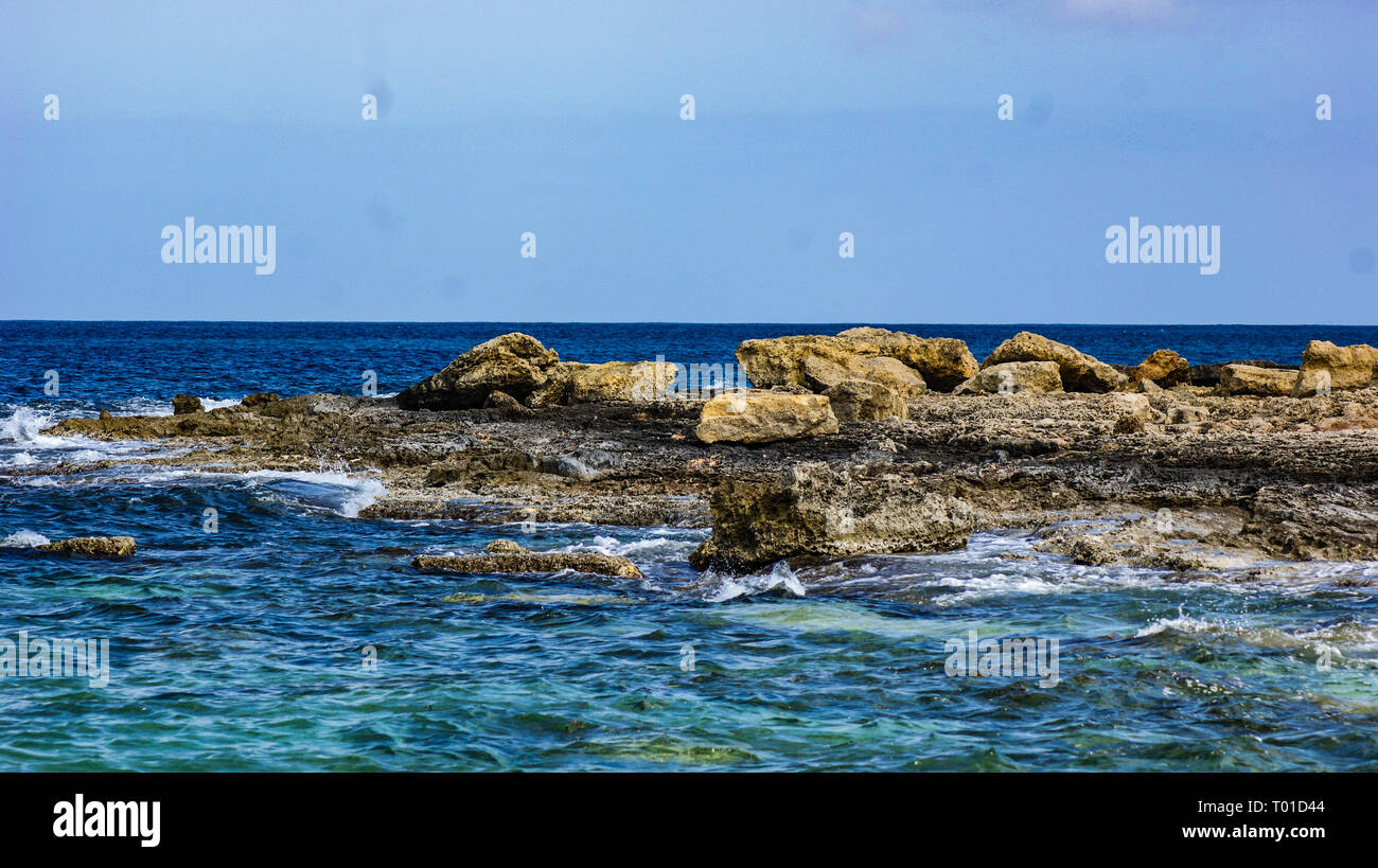Il mare Mediterraneo rompe su una roccia costa sull'isola di Malta Foto Stock
