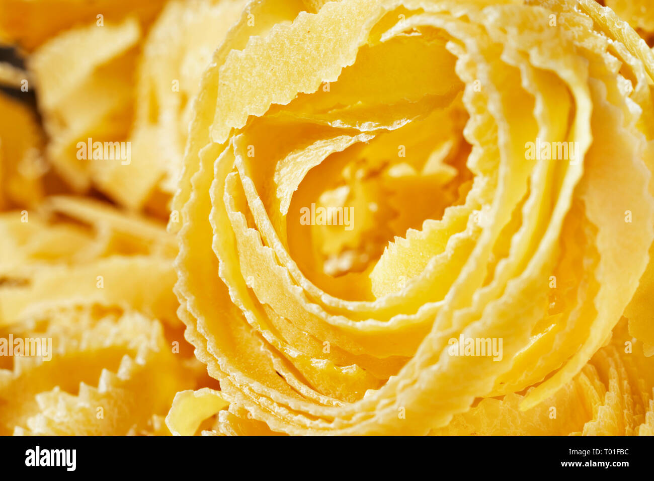 Bellissimo il nido di fettuccine close up , nastri sottili di pasta con bordi geometrica e superficie ruvida Foto Stock