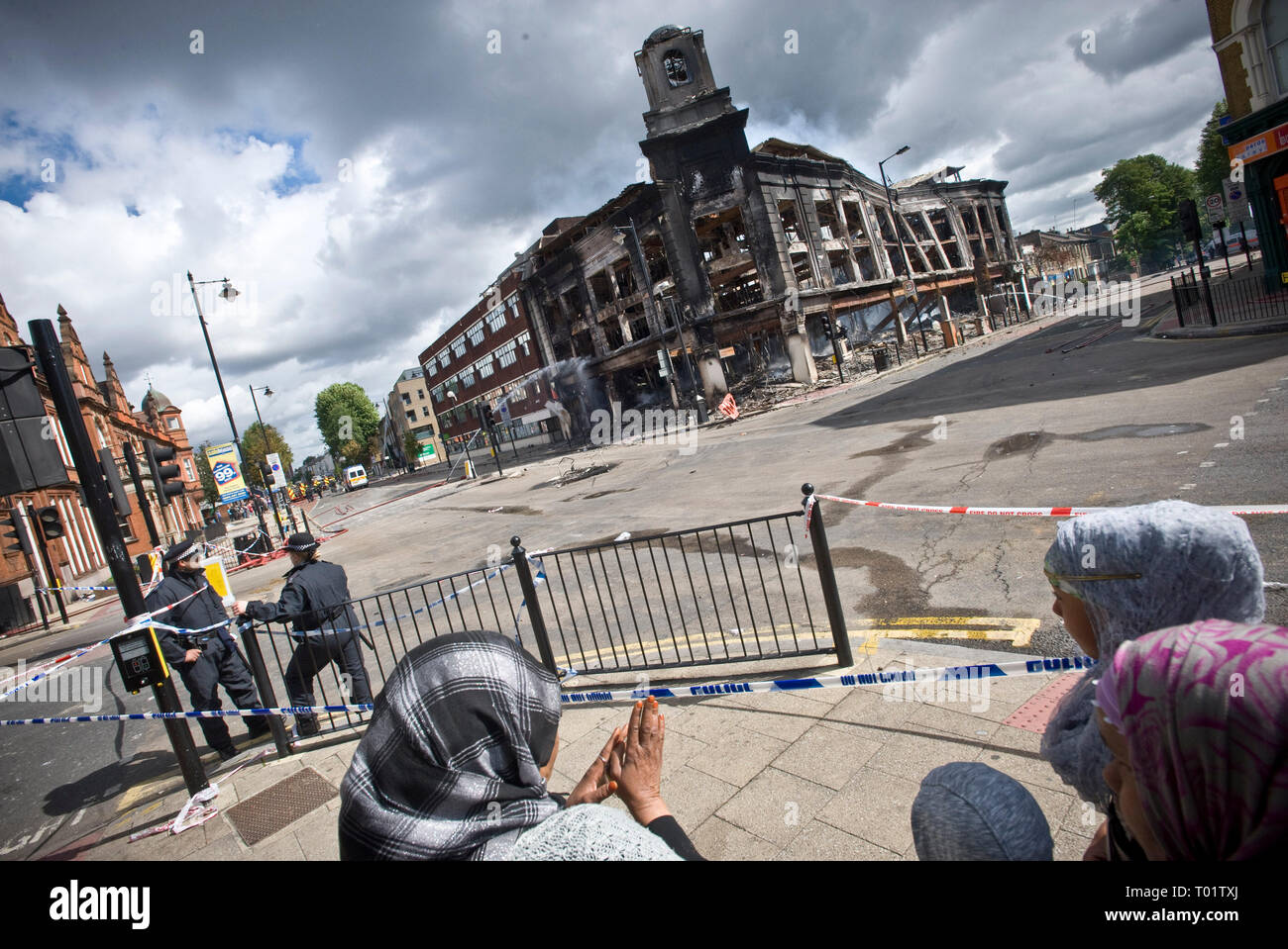 Conseguenze del Tottenham tumulti . I residenti locali indagine i danni compreso un bruciata la polizia van e tappeti negozio di destra distrutta da un incendio doloso . Il negozio edificio risale al 1930 . Local MP David Lammy è raffigurato visitando la scena con i consiglieri locali. Foto Stock