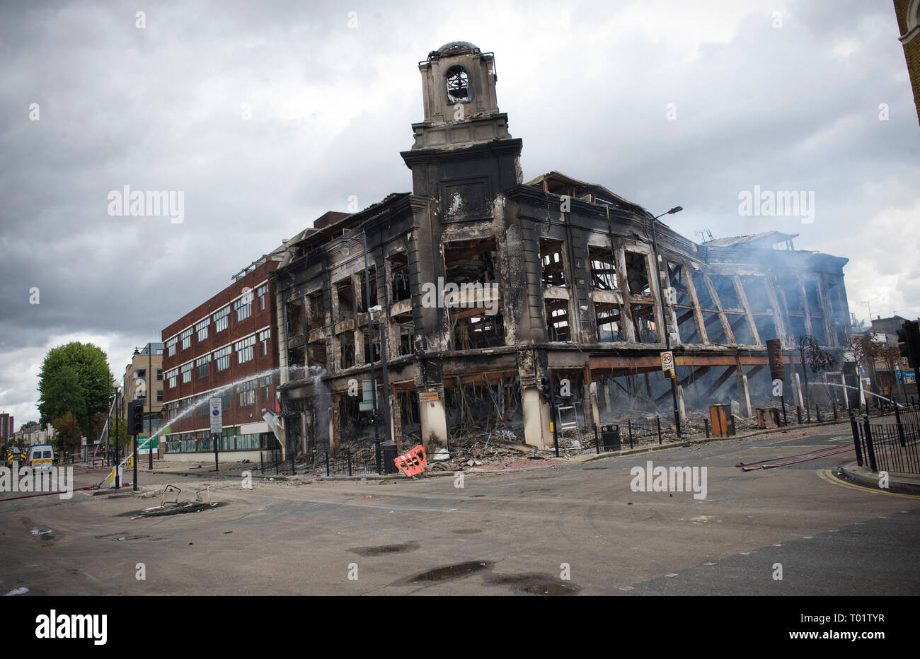 Conseguenze del Tottenham tumulti . I residenti locali indagine i danni compreso un bruciata la polizia van e tappeti negozio di destra distrutta da un incendio doloso . Il negozio edificio risale al 1930 . Local MP David Lammy è raffigurato visitando la scena con i consiglieri locali. Foto Stock