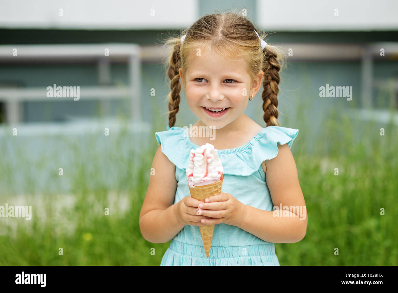 Una bambina cammina fuori e mangiare il gelato. Il concetto di infanzia, stile di vita, cibo, estate Foto Stock