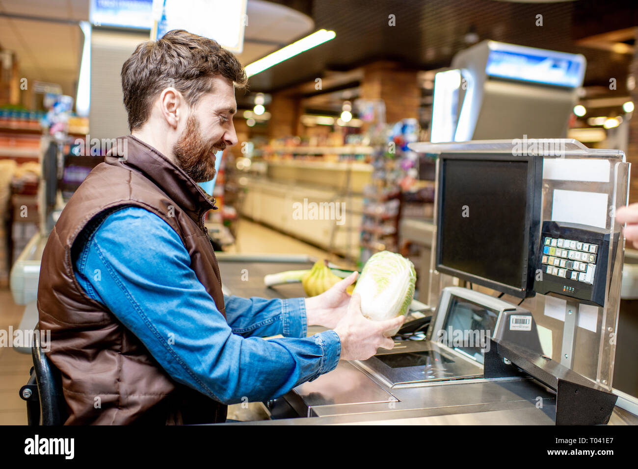 Felice cassiere lavora alla cassa del supermercato Foto Stock