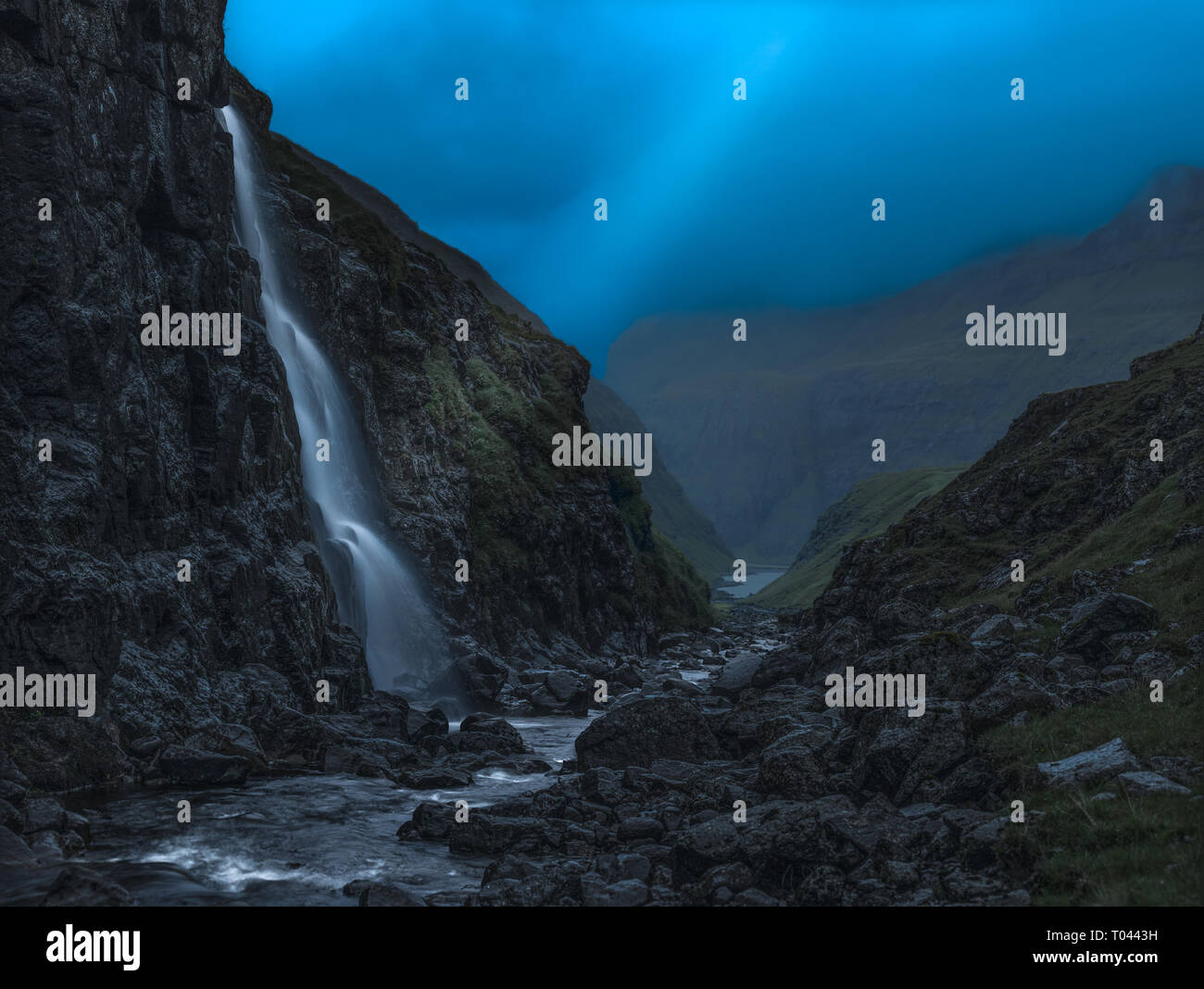 Lightbeam sulla cascata nella piccola valle al calar della sera, Isole Faerøer. Foto Stock