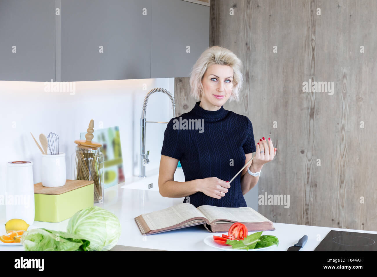 Giovane donna bionda la cottura nella cucina moderna Foto Stock