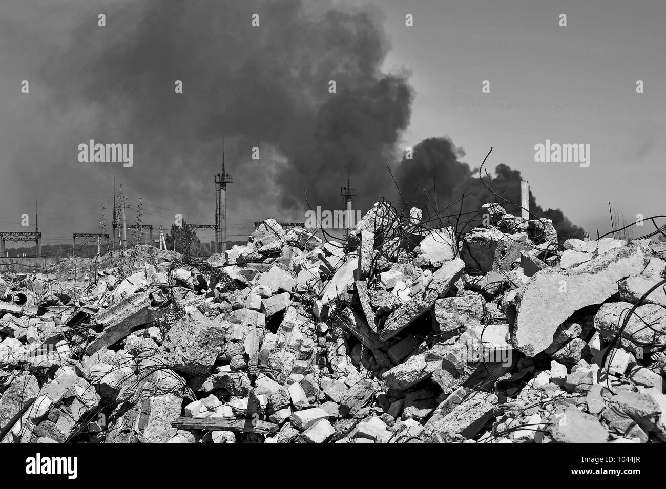 Un mucchio di macerie di cemento con sporgente rebar sullo sfondo di uno spessore di fumo nero nel cielo. Sfondo. Il concetto delle conseguenze di huma Foto Stock