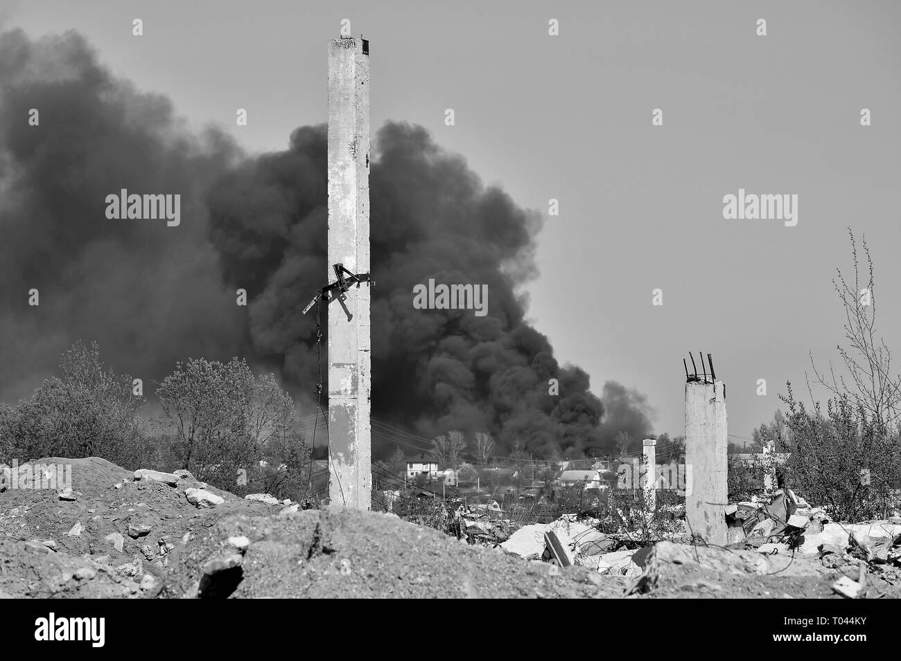 Un mucchio di macerie di cemento con sporgente rebar sullo sfondo di uno spessore di fumo nero nel cielo blu. Sfondo. Il concetto delle conseguenze di Foto Stock