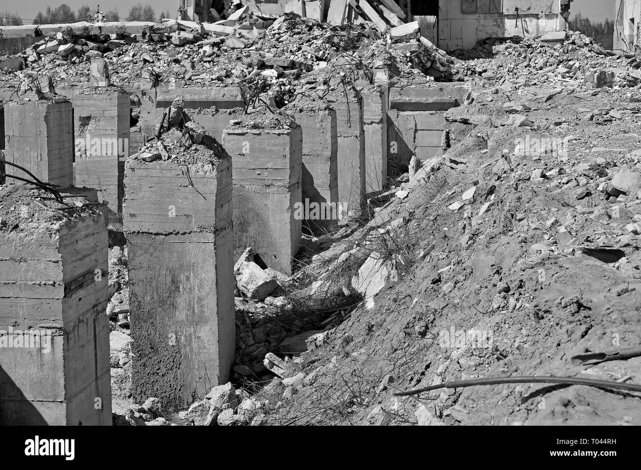 I resti delle fondamenta in calcestruzzo di una grande struttura in forma di pile distrutte, pietre, terra e argilla. In bianco e nero. Foto Stock