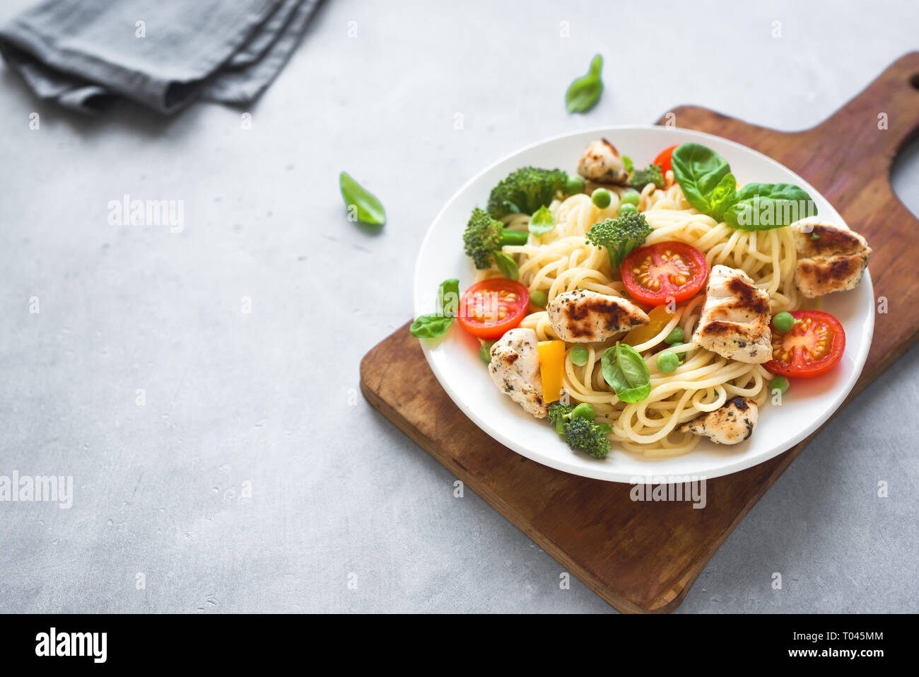 Il pollo e le verdure con la pasta. Spaghetti con grigliate di carne di pollo e verdure e basilico, vista dall'alto, copia dello spazio. Pasta di stagione primavera ricetta. Foto Stock