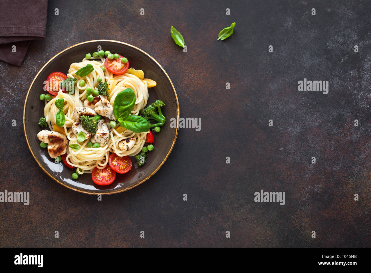 Il pollo e le verdure con la pasta. Spaghetti con grigliate di carne di pollo e verdure e basilico, vista dall'alto, copia dello spazio. Pasta di stagione primavera ricetta. Foto Stock