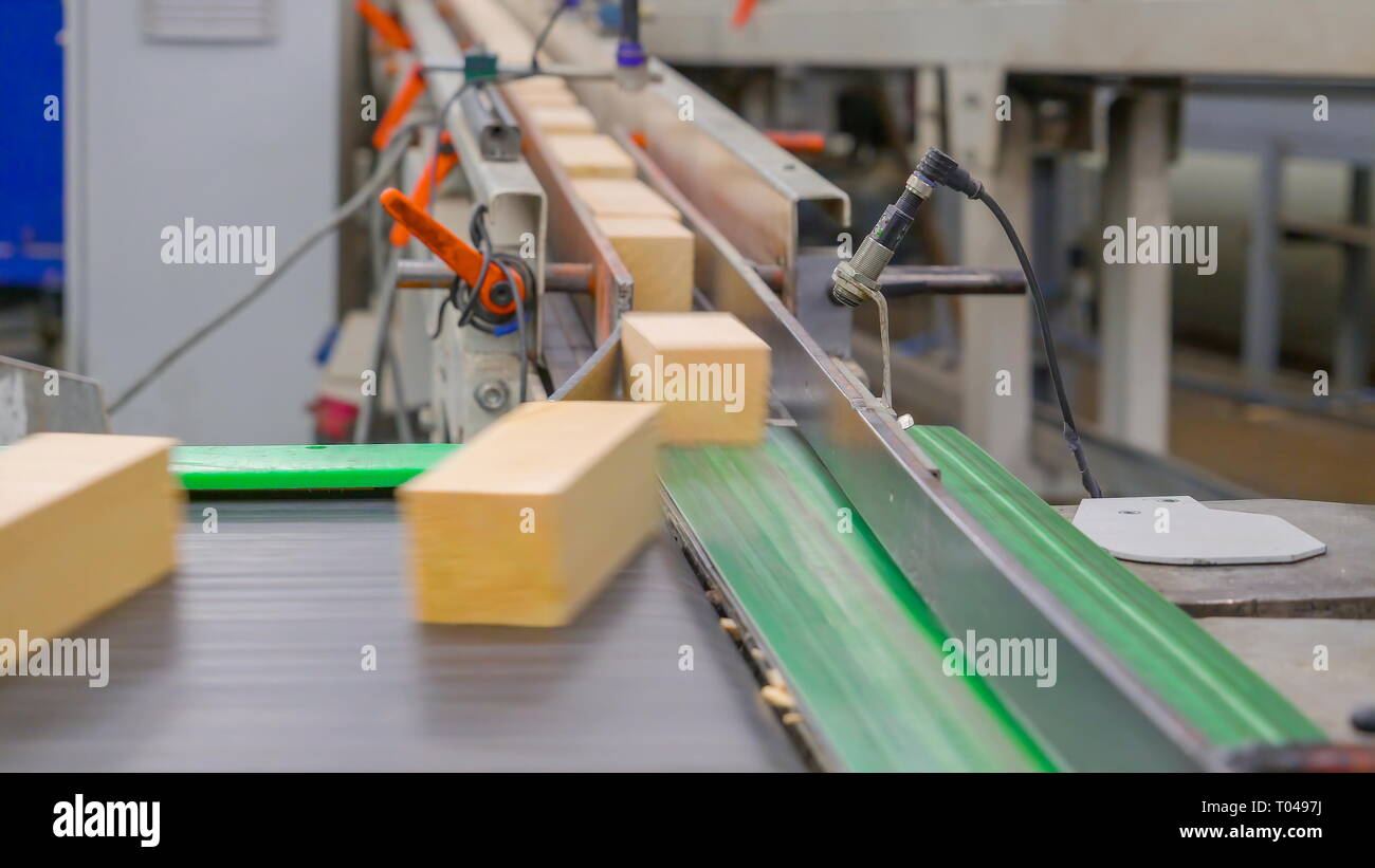 Sguardo ravvicinato di piccoli blocchi di legno in movimento dalla macchina all'interno della segheria Foto Stock