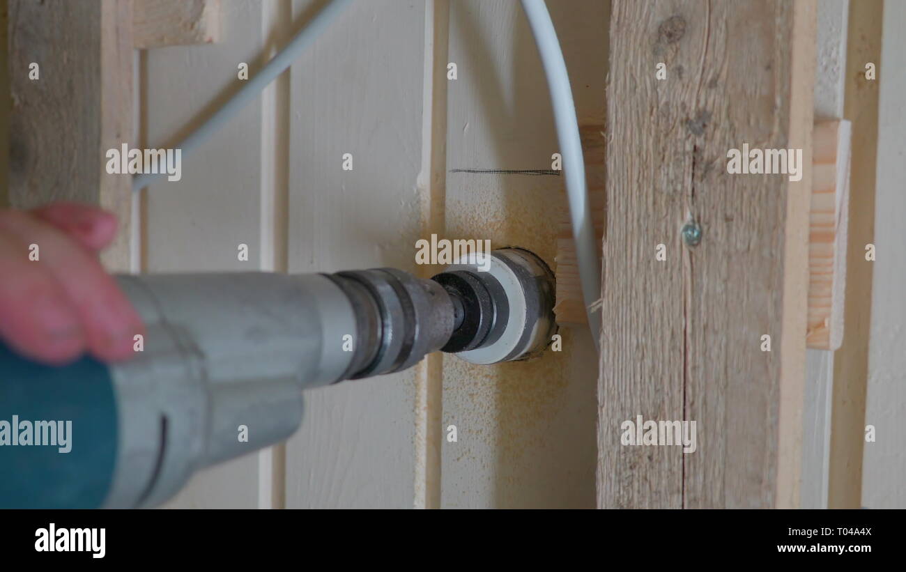 Un utensile di foratura a realizzare un foro sulla parete di legno della casa di mettere i cablaggi sull'elettricità Foto Stock