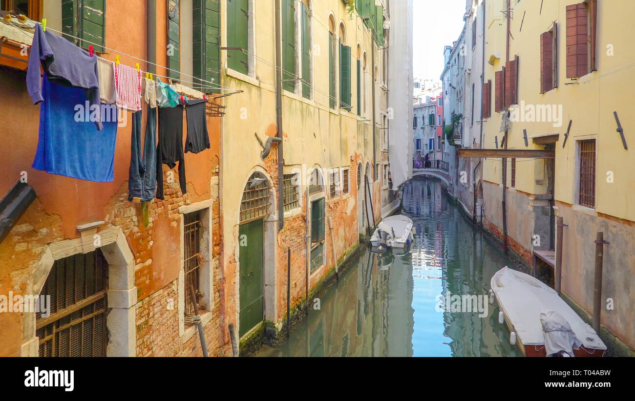 Il piccolo canale nella città di Venezia circostante con edifici e case e gli indumenti appesi fuori in Italia Foto Stock
