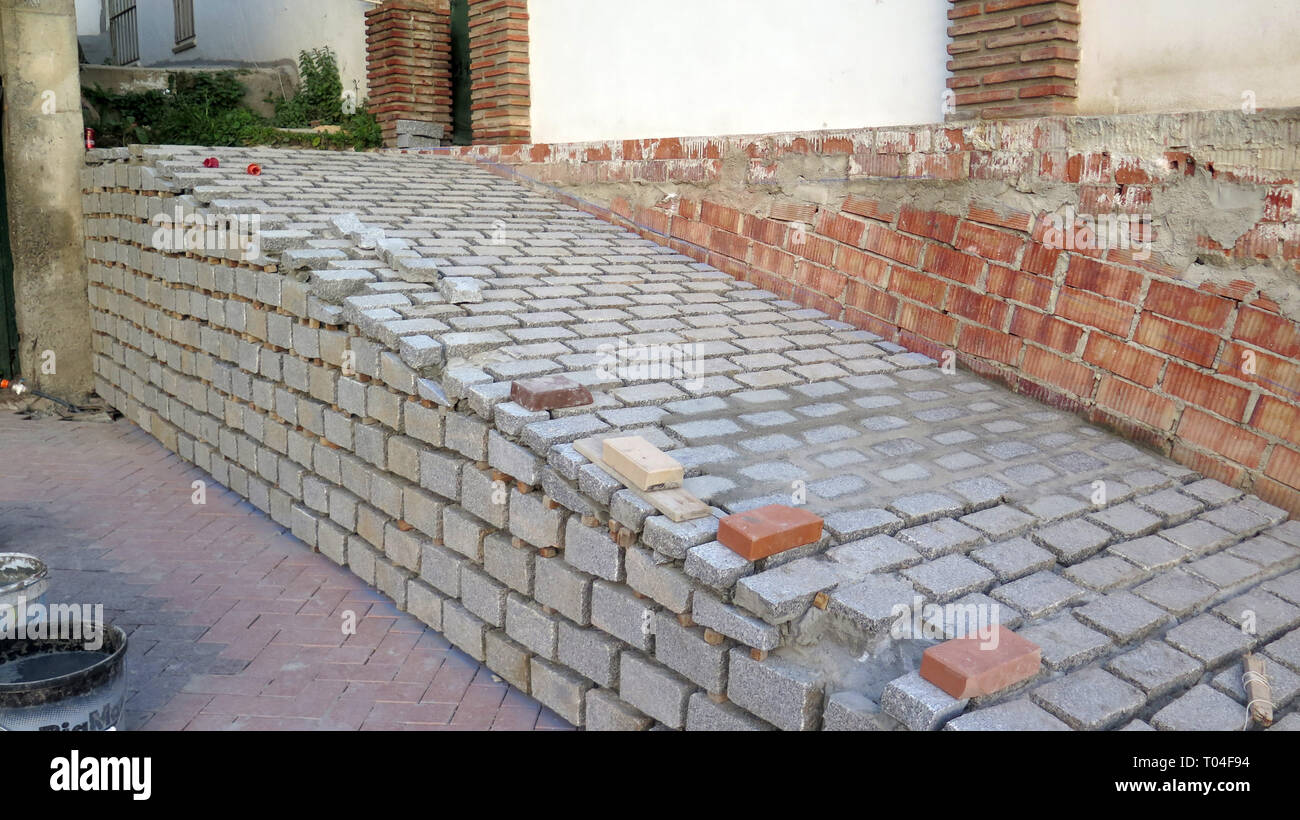 Square pietre per pavimentazione in attesa di iniezioni sul pendio nel villaggio andaluso di riconversione Foto Stock