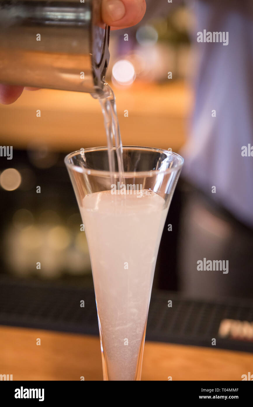 Versando frizzanti cocktail in a tall class close up Foto Stock