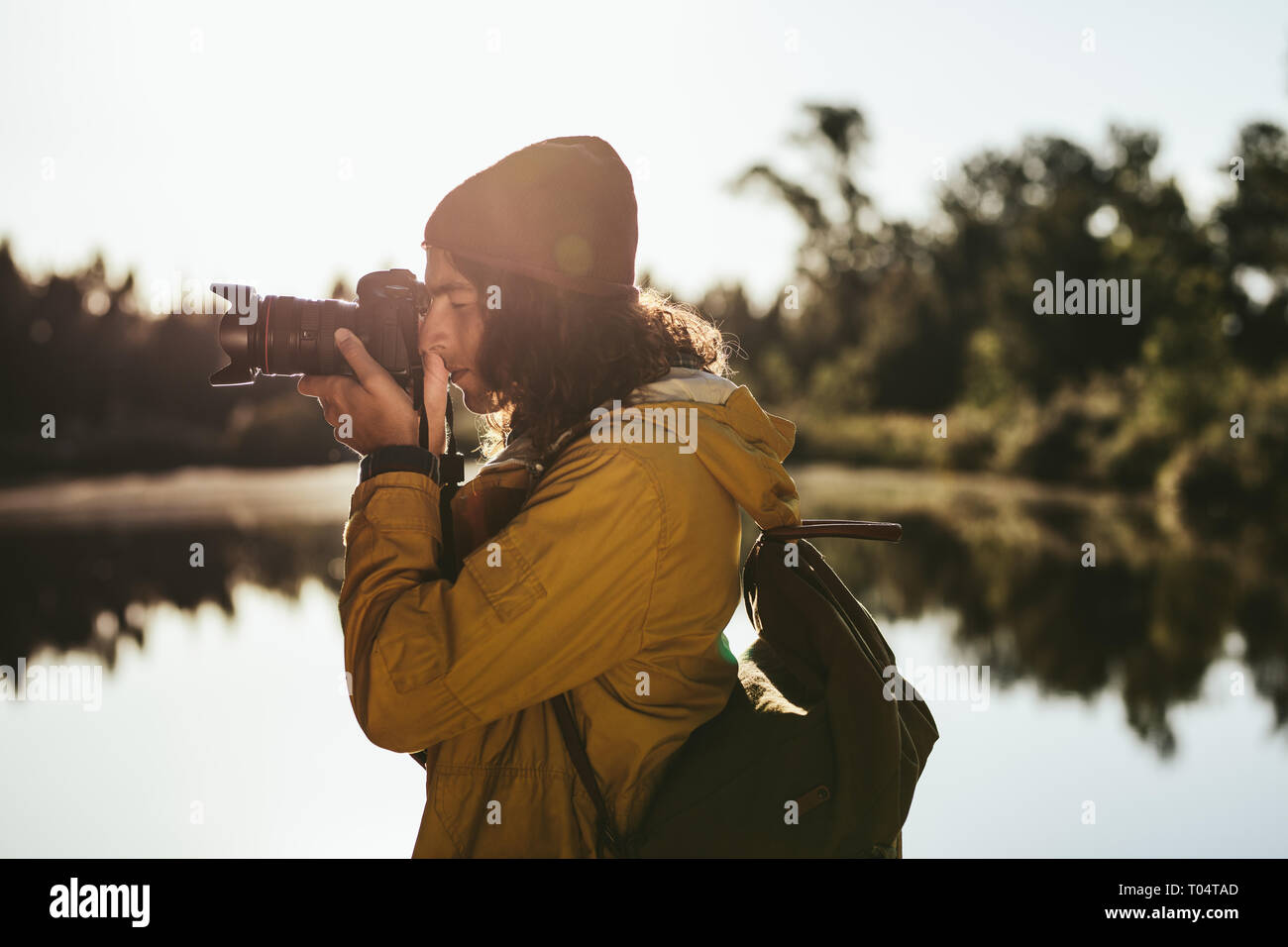 Turistica prendendo una foto con una fotocamera reflex digitale. Vista laterale di un viaggiatore alla ricerca nella sua fotocamera digitale per scattare una foto. Foto Stock