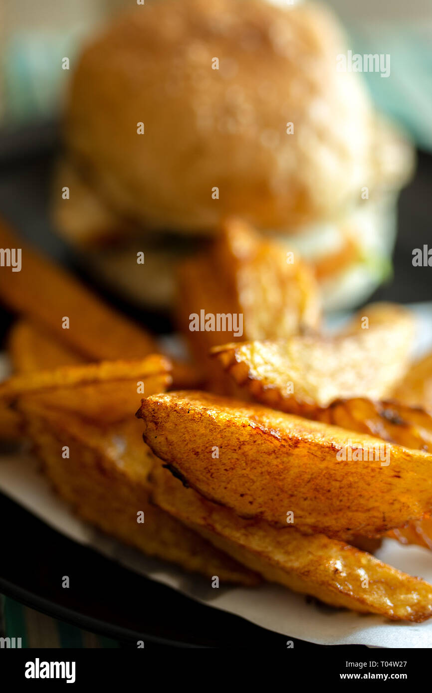 Piastra di saporite tagliate a mano fritto alla perfezione patatine fritte con hamburger di manzo in pane bun. Foto Stock