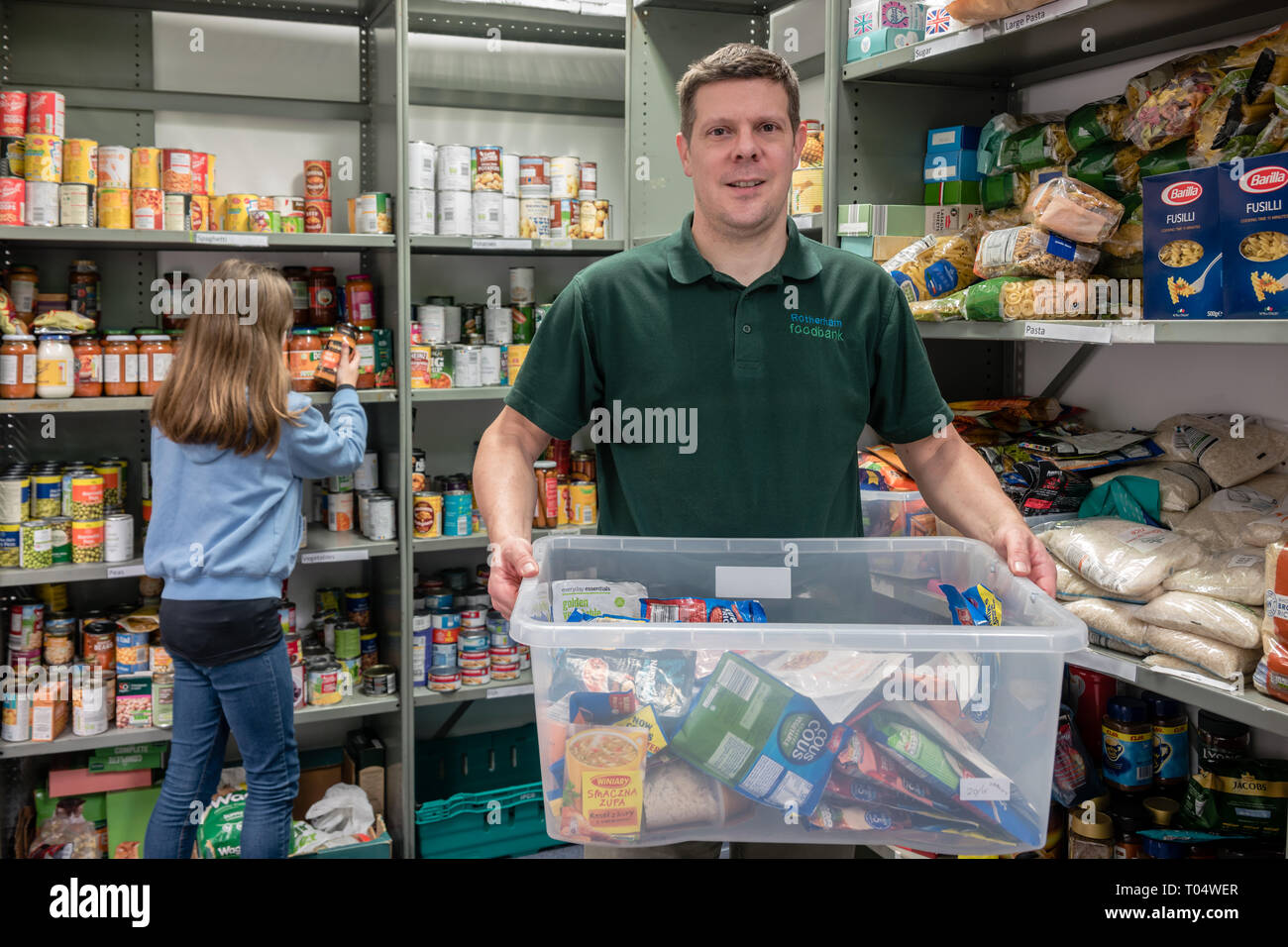 Dei volontari in un Regno Unito Trussell fiducia chiesa locale food bank ripiani di imballaggio e tenendo le donazioni Foto Stock