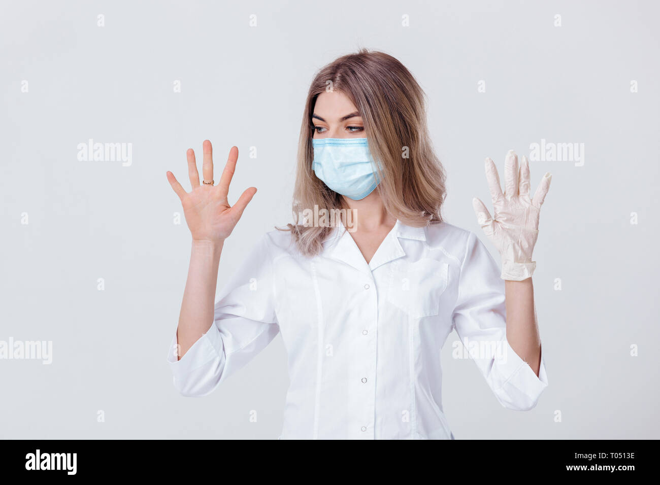Ritratto di donna medico con una maschera facciale medico mostra le mani. una mano e l'altra senza Foto Stock