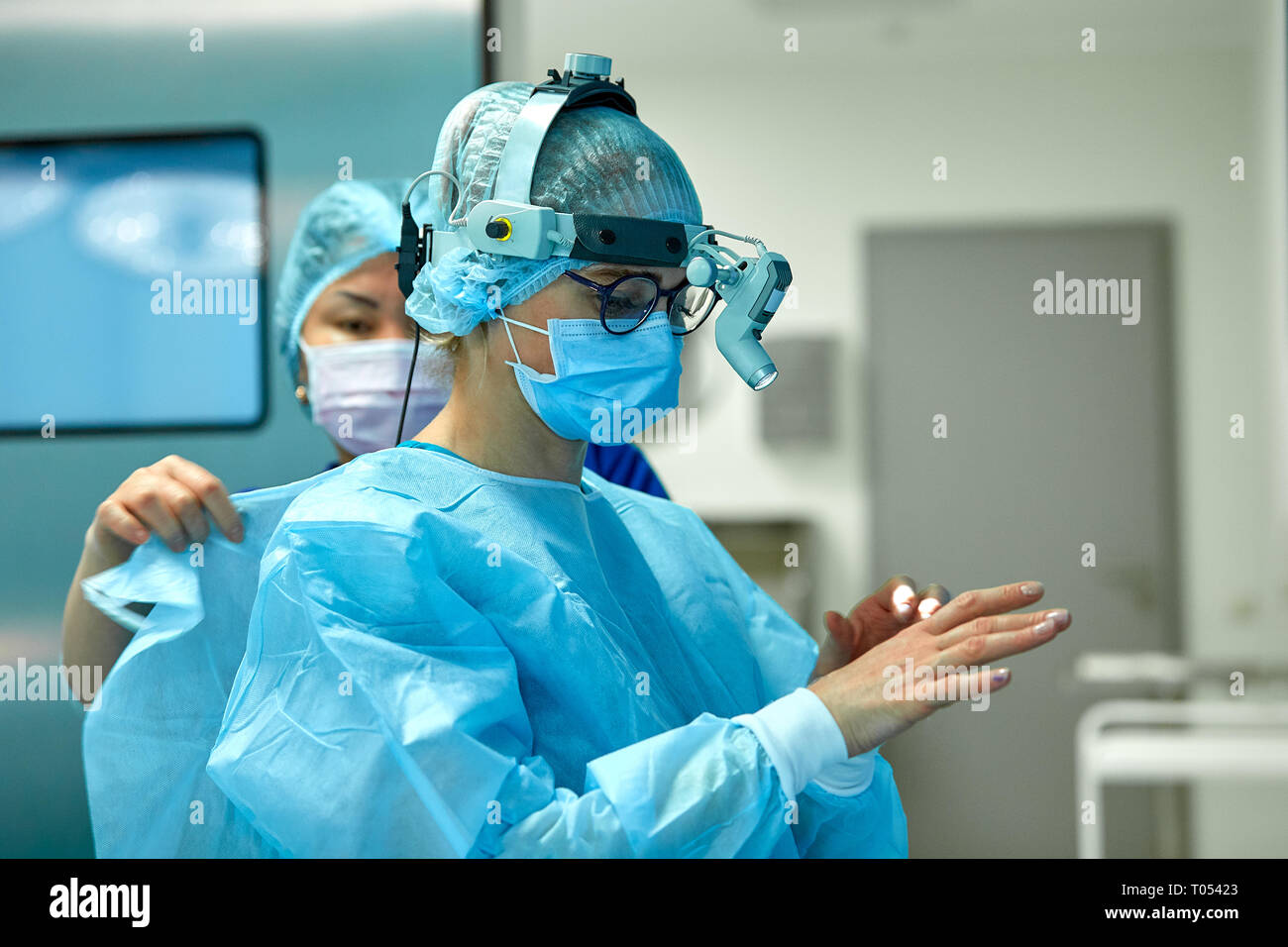 I chirurghi indossare abbigliamento sterile prima di un intervento  chirurgico. Un team di chirurghi la preparazione per la chirurgia,  impostare la luce aggiuntiva sulla testa Foto stock - Alamy