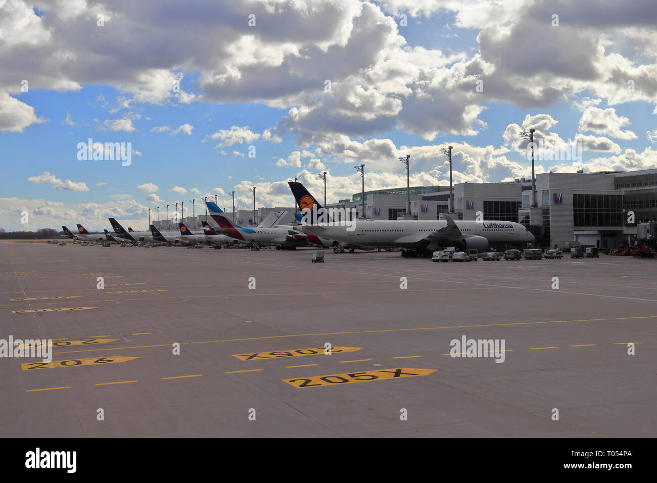 Aeroporto di Monaco di Baviera, Germania - 13 Marzo 2019: Il terminale come visto dal Piazzale e aerei Lufthansa in diversi tipi di livrea con gru emblema. Foto Stock