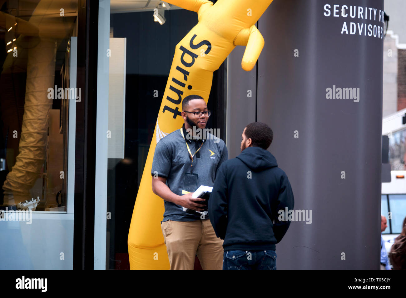 Un dipendente si impegna con un membro del pubblico sul marciapiede fuori da un negozio Sprint nel centro di Philadelphia, PA il 15 marzo 2019. Foto Stock