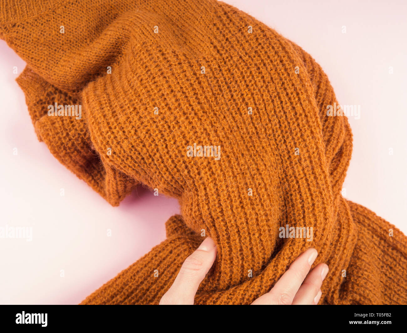 Accogliente maglione giallo in rosa con la donna la mano tenendolo Foto Stock