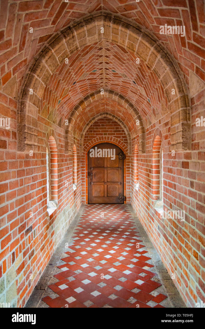Antiche in legno porta alla fine del corridoio di mattoni Foto Stock