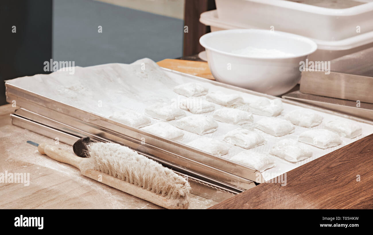 La formazione di pezzi di pasta per torte (pasties) su una superficie di legno infarinate Foto Stock