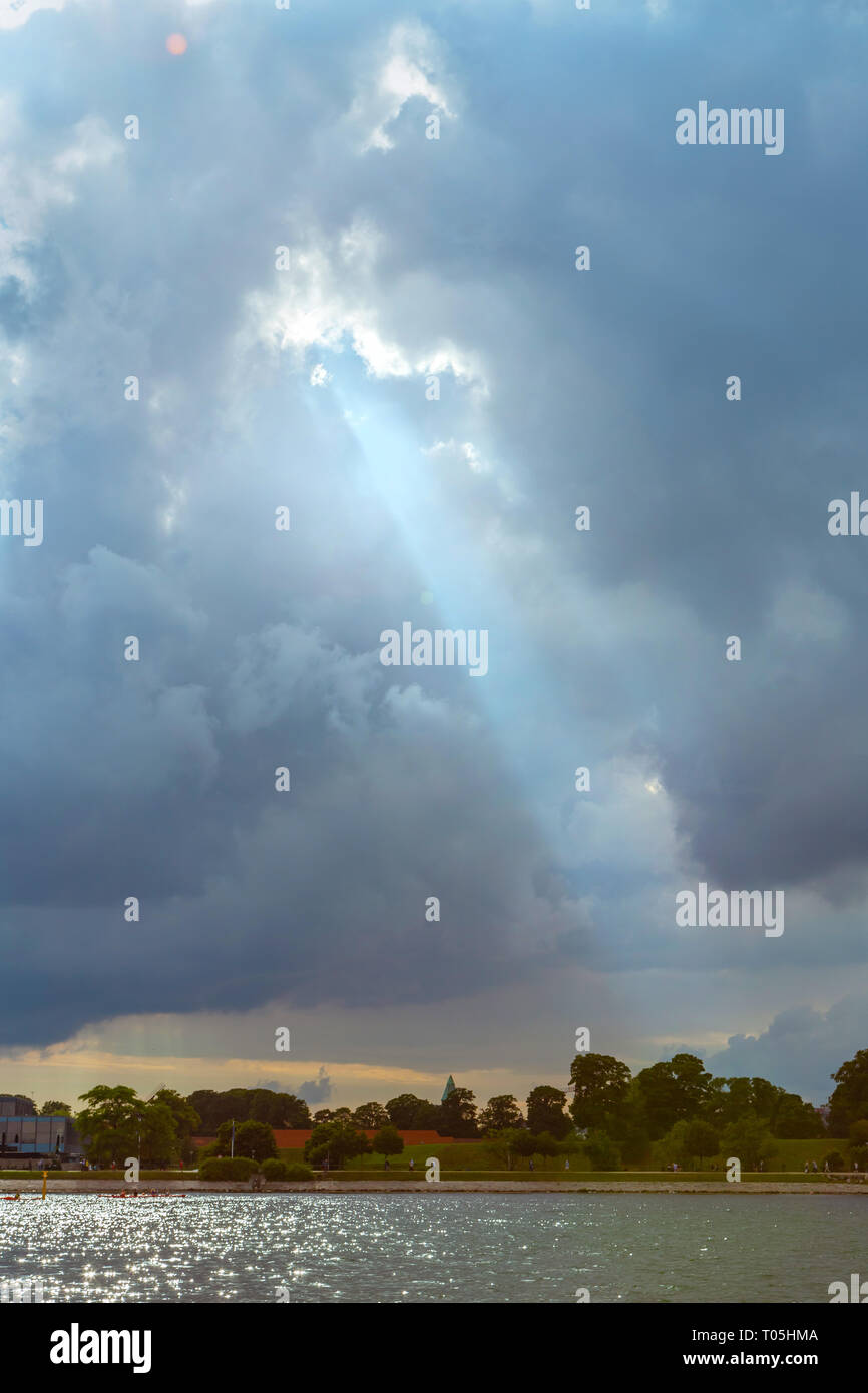 Raggi di sole che splende attraverso cielo nuvoloso scuro Foto Stock