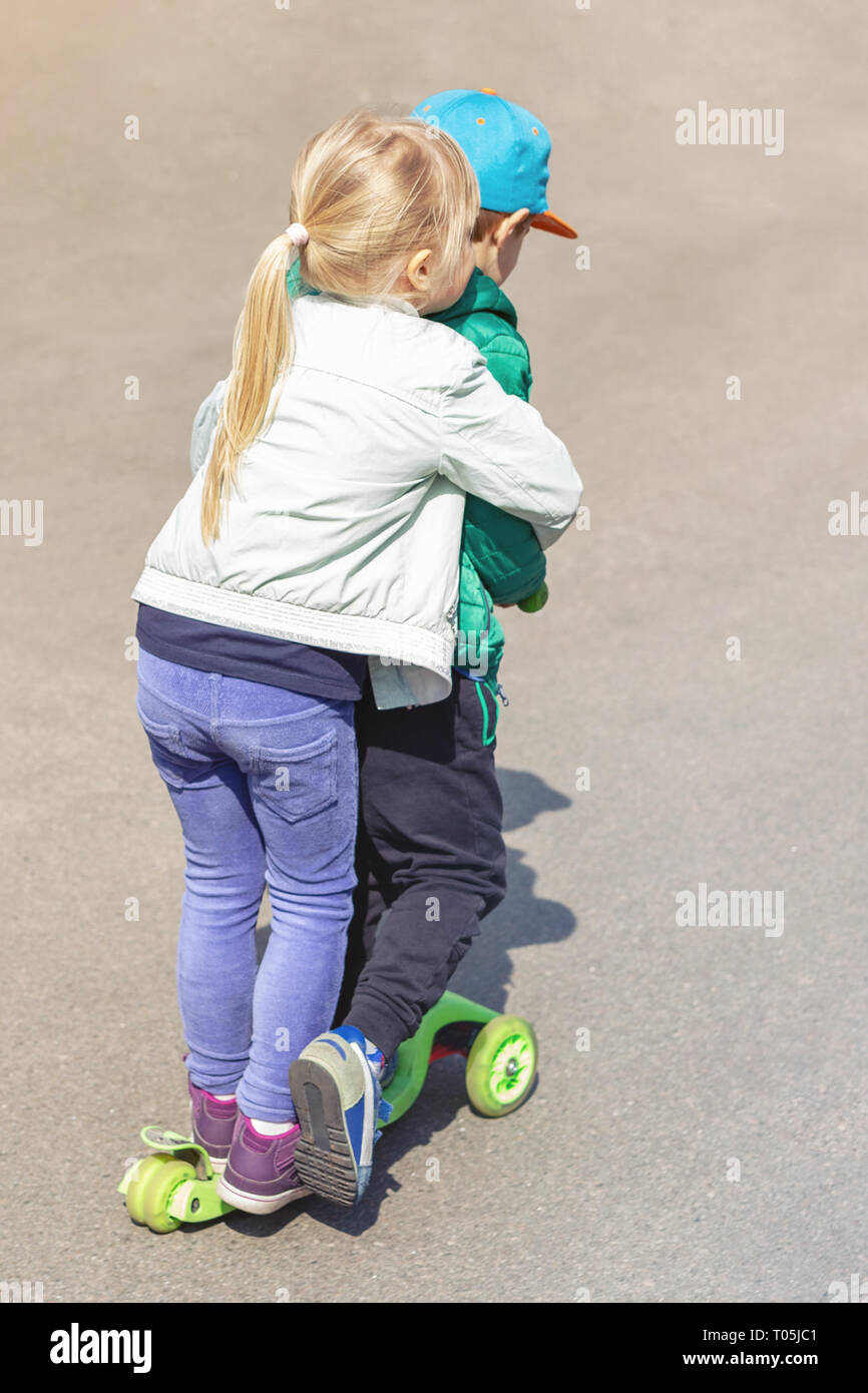 Due frineds un ragazzo e una ragazza divertirsi in sella a uno scooter insieme simultaneamente. Bambini i fratelli, fratello e sorella godendo outdoor sport activitie Foto Stock