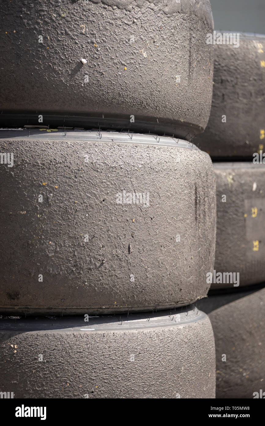 Una pila di motorsport racing pneumatici che mostra i detriti della strada, verticale Foto Stock
