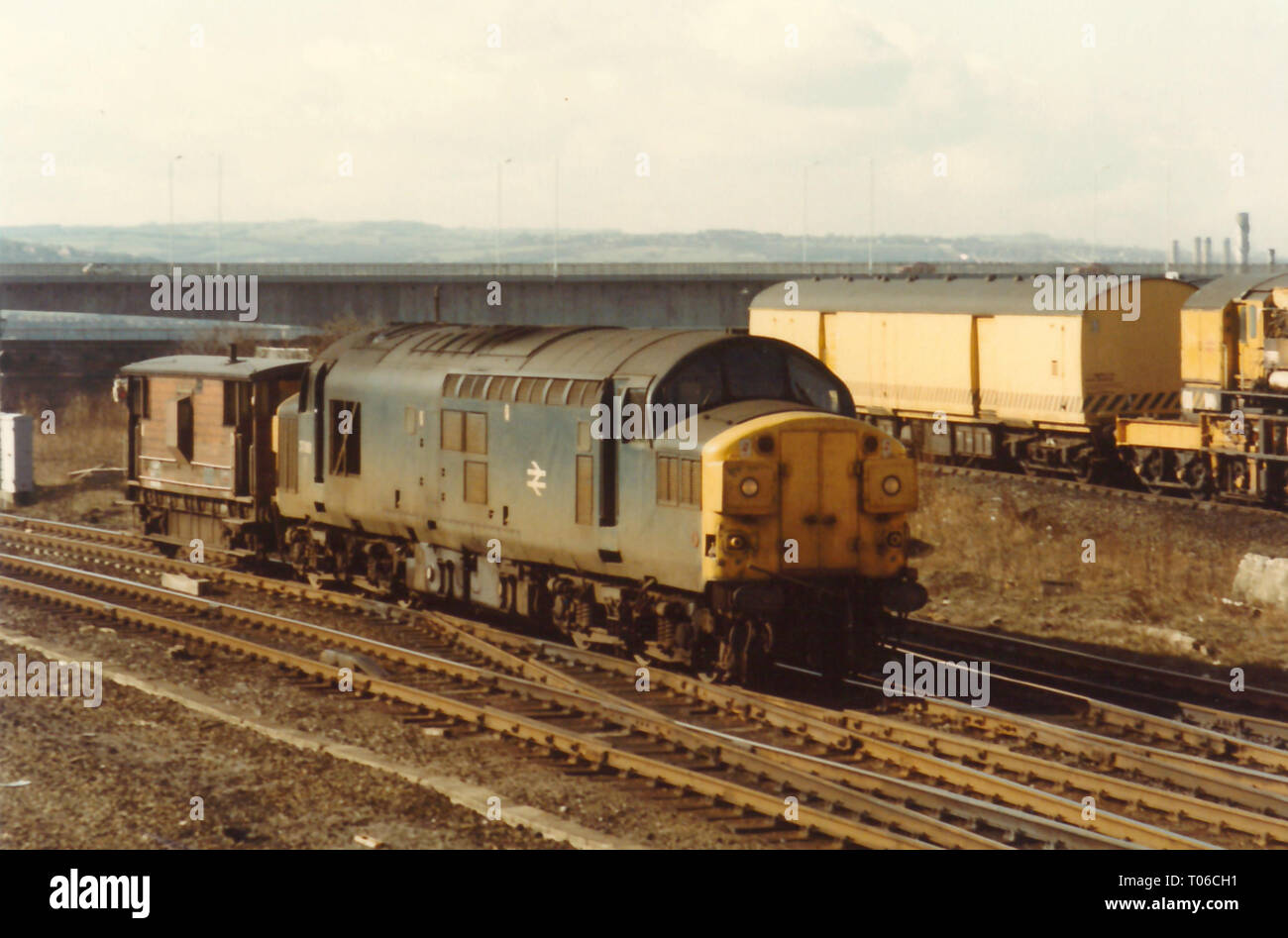 Classe 37 37088 costeggia Gateshead depot con un guardie van il 5 marzo 1985 con una ripartizione gru e Redheugh Bridge in background. Foto Stock