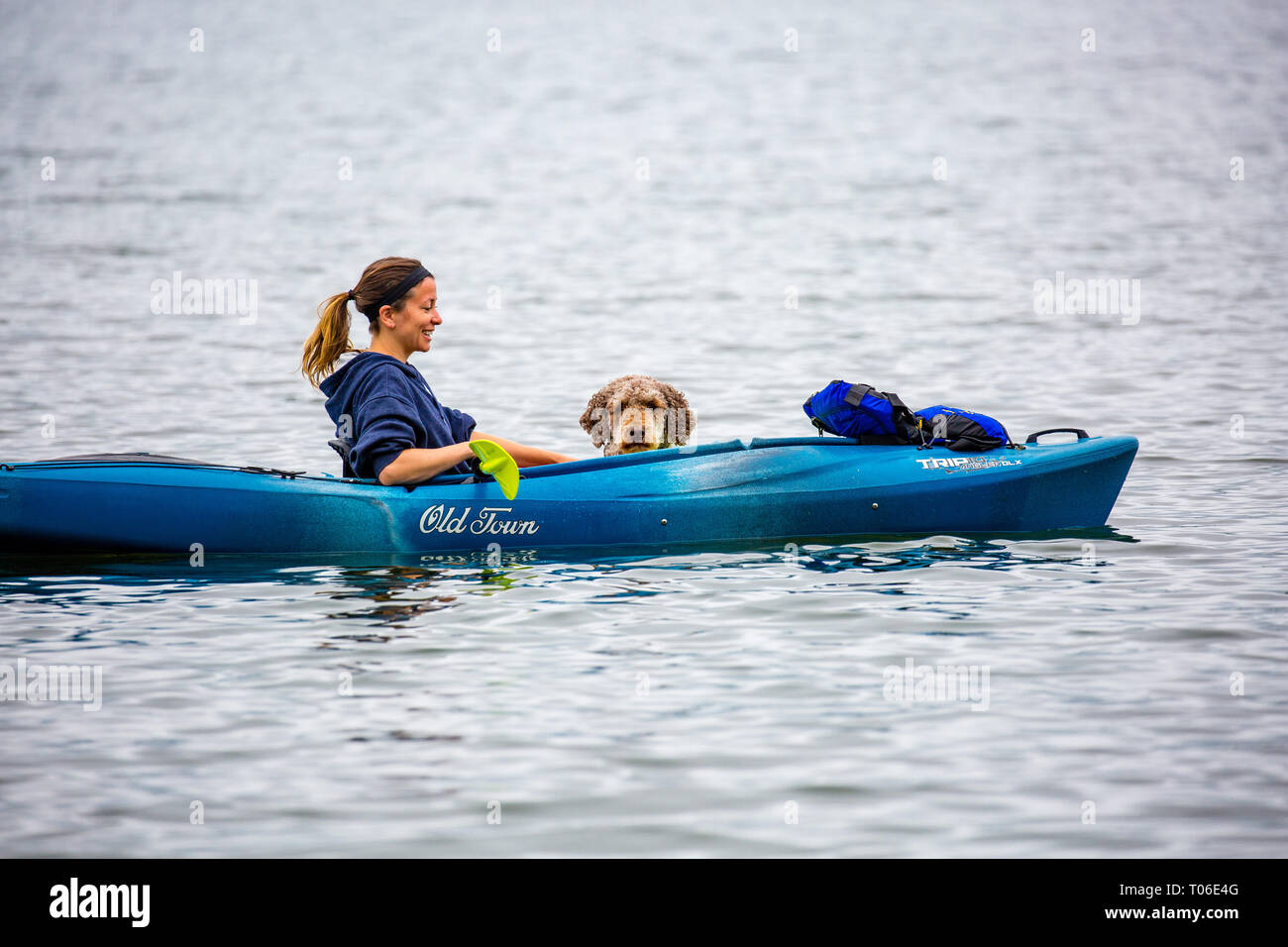 Pickeral, Wisconsin, USA Giugno 12, 2018. Ragazza sorridente mentre è seduto in una vecchia città Kayak con il suo cane nel lago di gru. Foto Stock