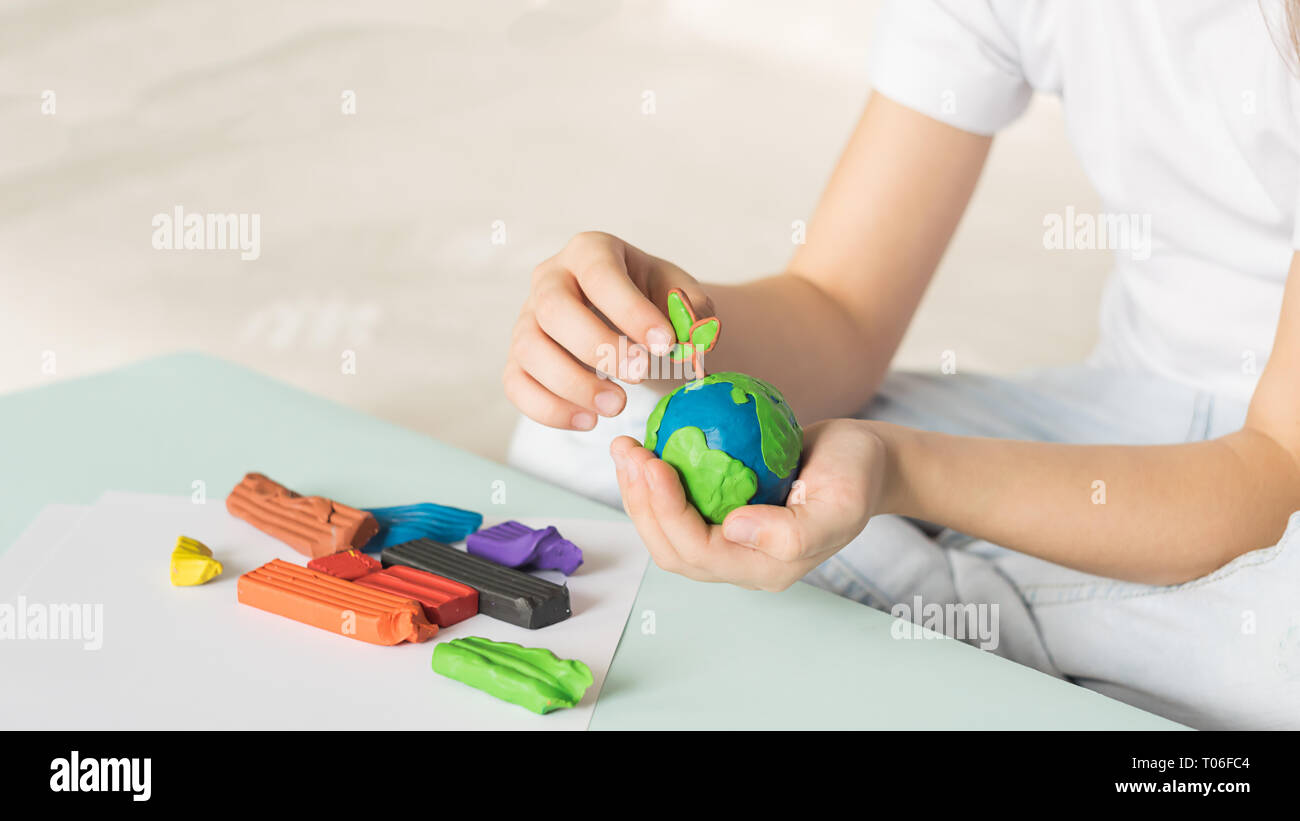 Il fanciullo scolpisce da plastilina il globo e alberi. La posizione del pianeta in bambini di palme. Concetto di ecologia. Foto Stock