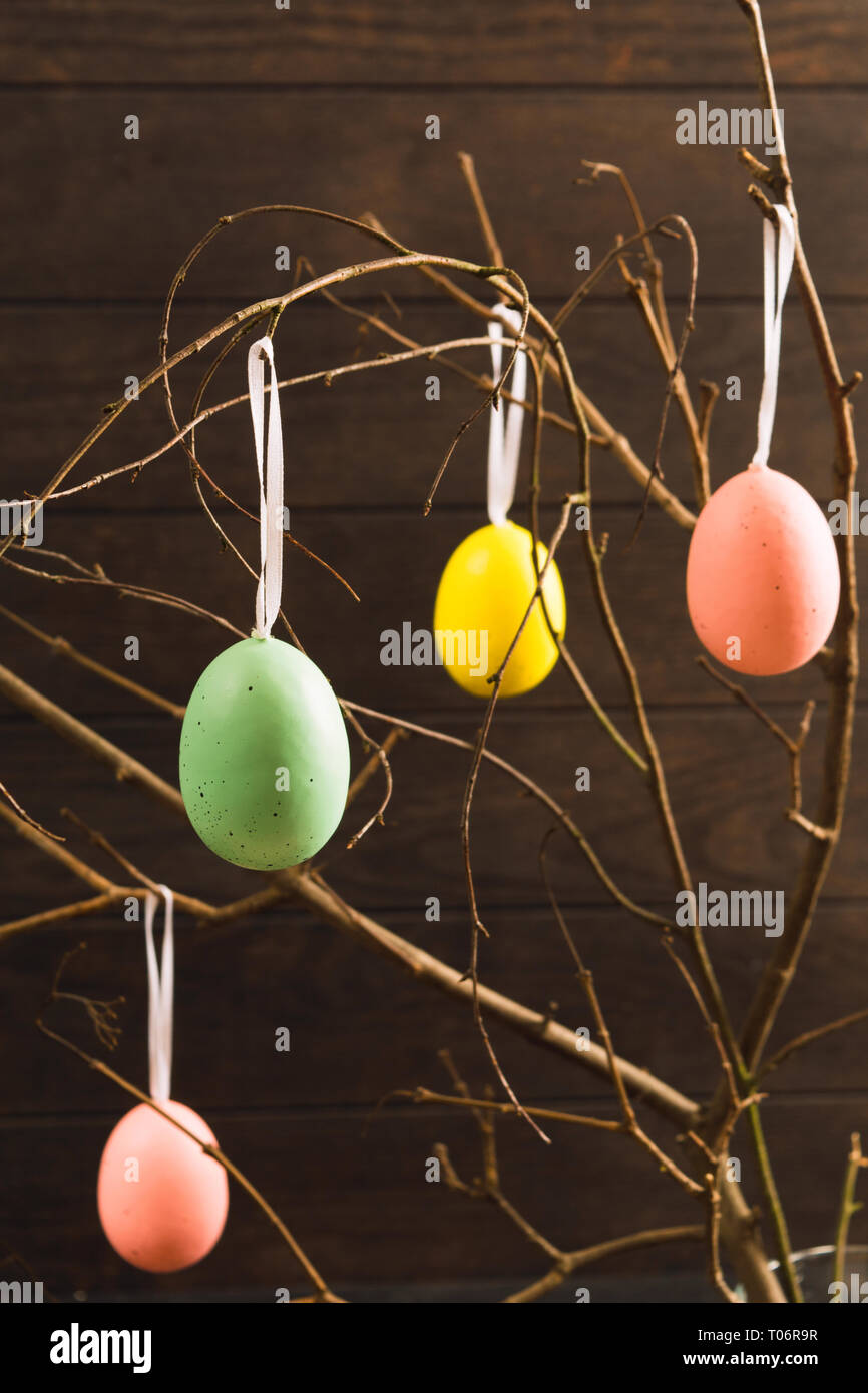 Pasqua uova colorate su albero con legno scuro sfondo, colpo verticale Foto Stock