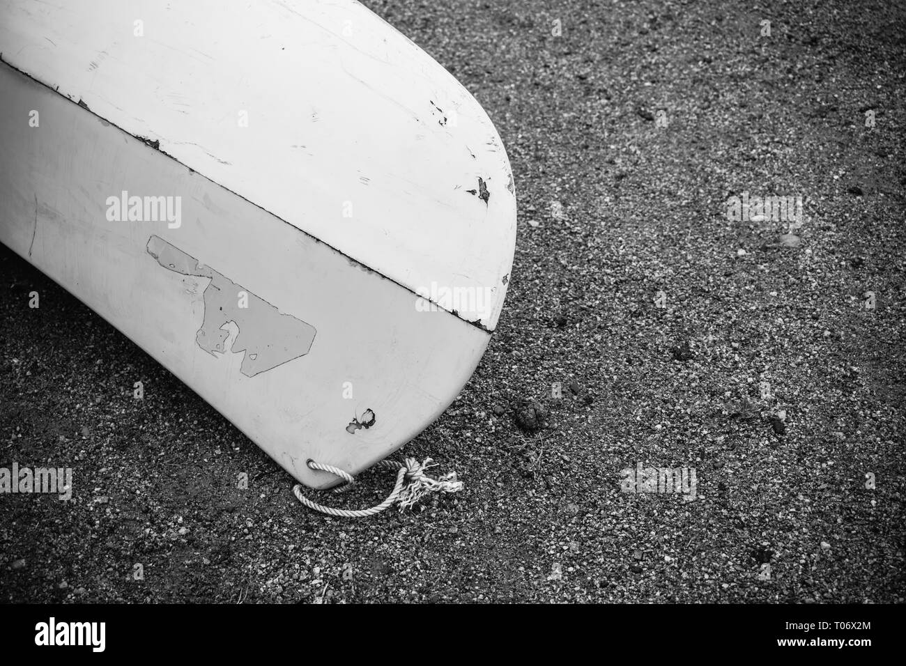 I kayak da bianco di plastica in fibra di vetro con età compresa tra i marchi con cordone bianco sulla spiaggia di sabbia nera con pietre sul mare con nessun popolo, sfondo Foto Stock