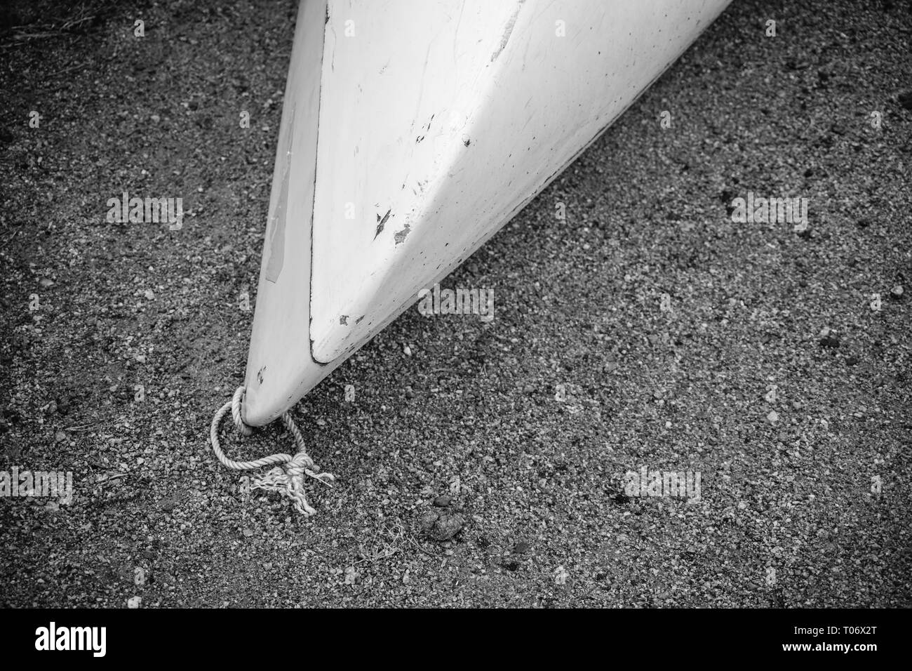 I kayak da bianco di plastica in fibra di vetro con età compresa tra i marchi con cordone bianco sulla spiaggia di sabbia nera con pietre sul mare con nessun popolo, sfondo wit Foto Stock