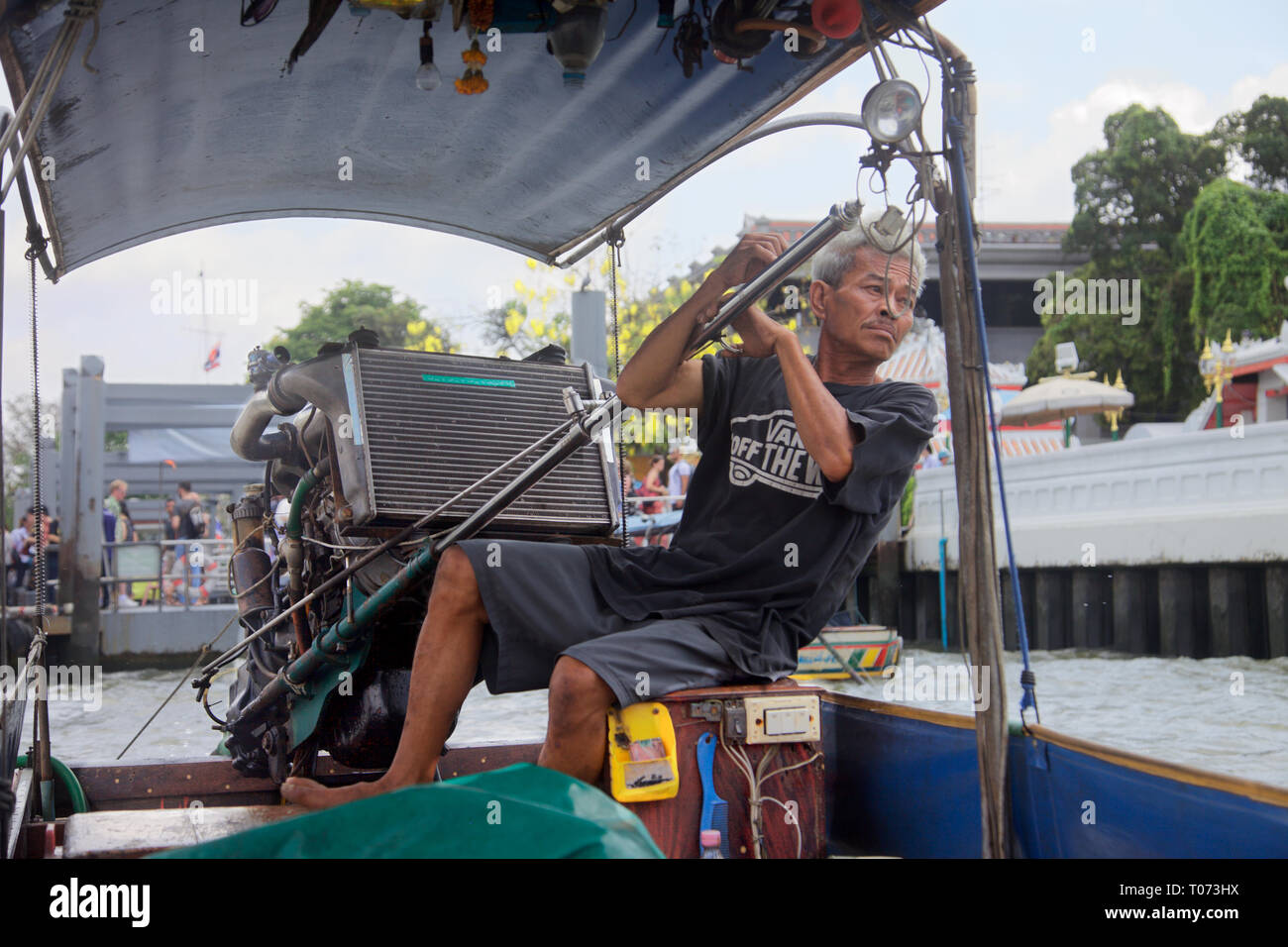 Un tailandese uomo alla guida di una lunga pinna alti imbarcazione turistica sul Fiume Chao Phraya. Bangkok, Thailandia Foto Stock