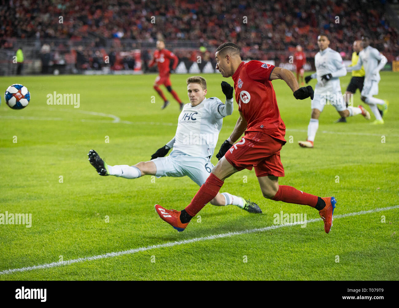 Toronto, Canada. Xvii Mar, 2019. Justin Morrow (anteriore) di Toronto FC passa la palla come Scott Caldwell(2 L) della Nuova Inghilterra rivoluzione difende durante il 2019 Major League Soccer (MLS) corrispondono al BMO Field di Toronto, Canada, 17 marzo 2019. Credito: Zou Zheng/Xinhua/Alamy Live News Foto Stock