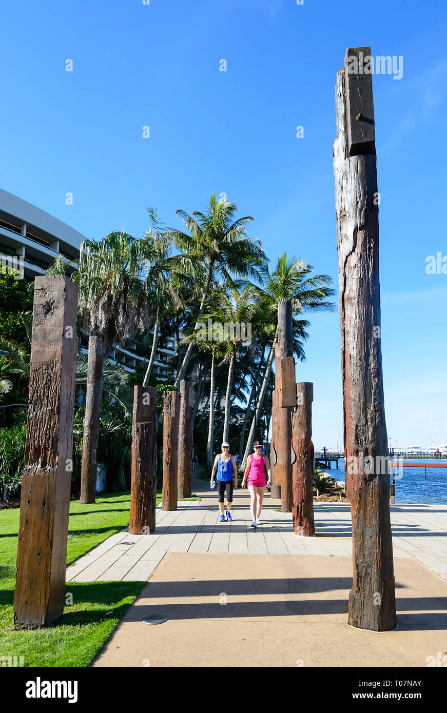 I pedoni a passeggio tra totem raffigurante passato di vita degli aborigeni nella zona Molo Marlin, Cairns, estremo Nord Queensland, FNQ, QLD, Australia Foto Stock